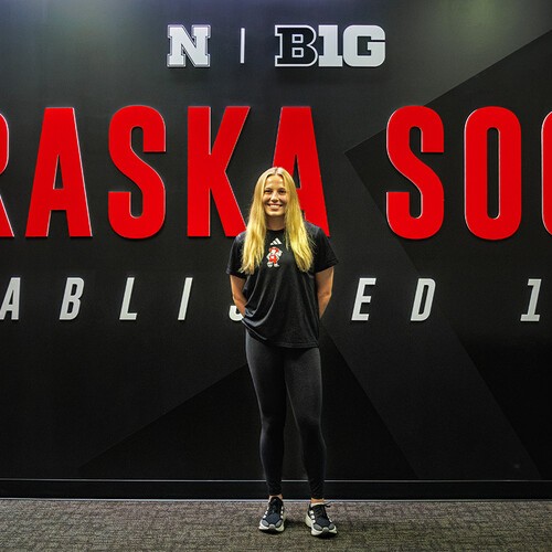 Ella Rudney in front of a Nebraska Soccer sign