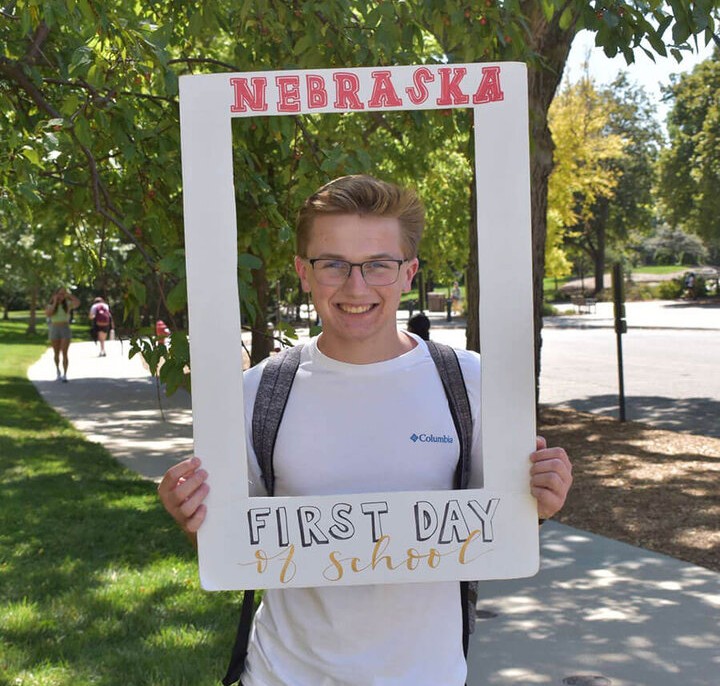 Nick holding a Nebraska-themed photo frame outdoors on a sunny day.