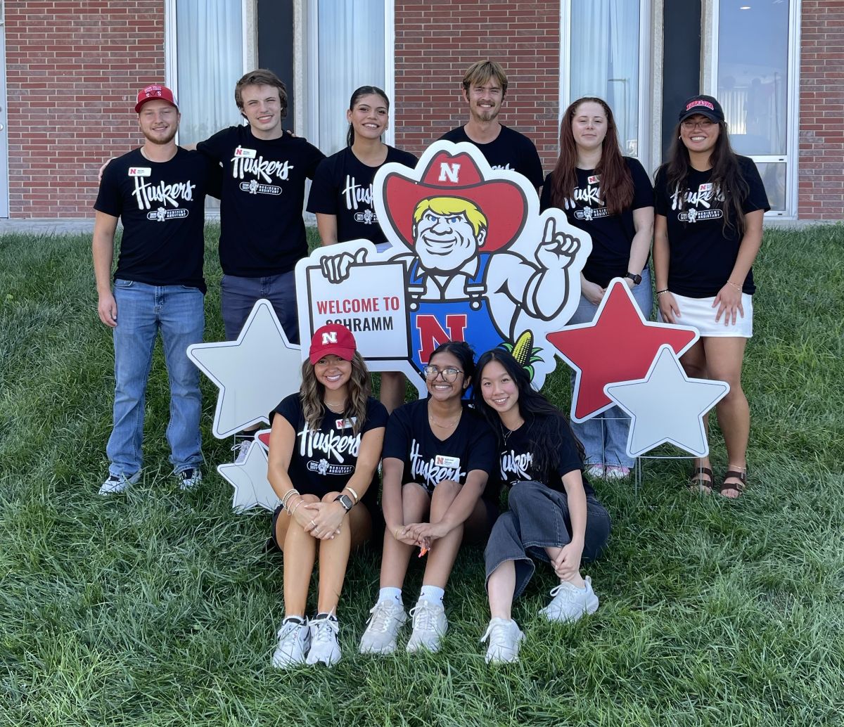 Subedi with a group of people smiling outdoors near a mascot cutout with red and white stars.