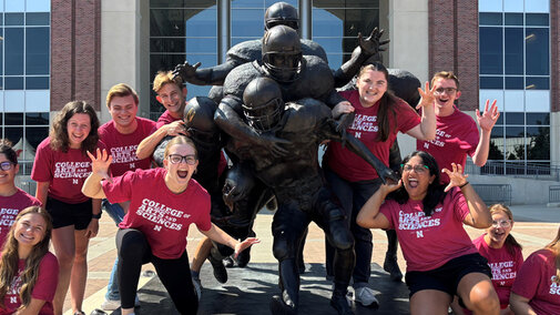 Ambassadors posing around statue in front of Memorial Stadium