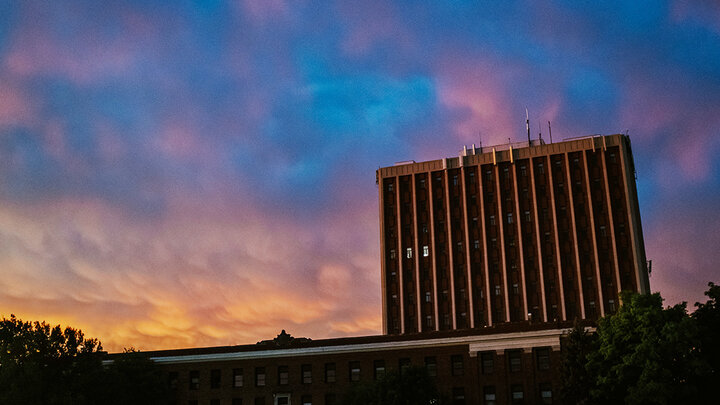 The sunrise behind Oldfather Hall casts blues and pinks into the sky.