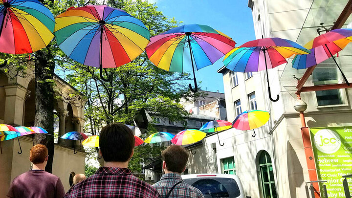 Colorful umbrellas hang over a street outside in Krakow, Poland.