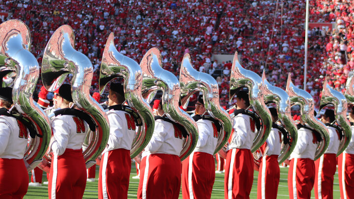 Ten sousaphone players perform in a line on the field at Memorial Stadium.