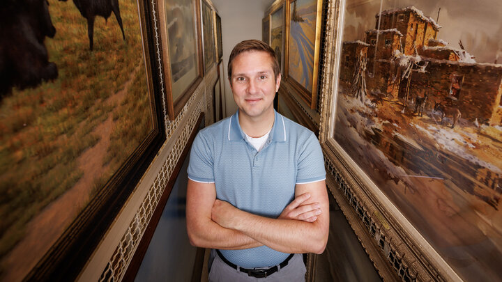 A man stands between paintings.