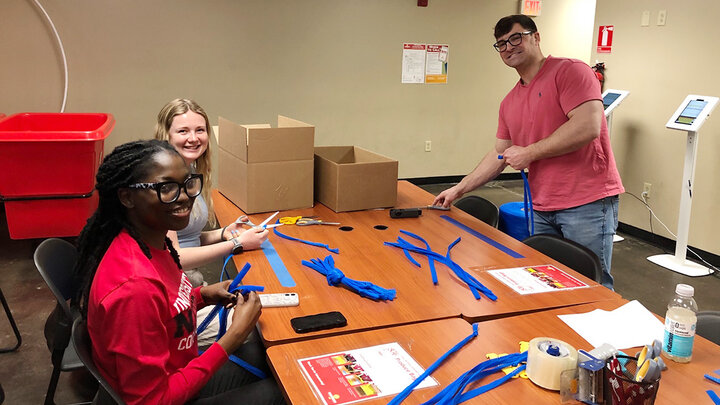 Promise Emmanuel (left), MaKenna Clinch and Ben Bentzinger assemble hygiene kits.