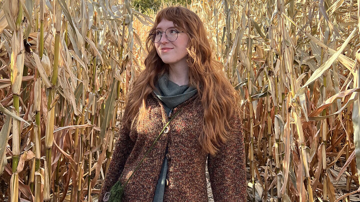 Lexi Thomas, undergraduate support specialist in the School of Biological Sciences, stands among cornstalks. She is among the female office/service staff who are being featured in March in a Q&A series organized by the Chancellor's Commission on the Status of Women.